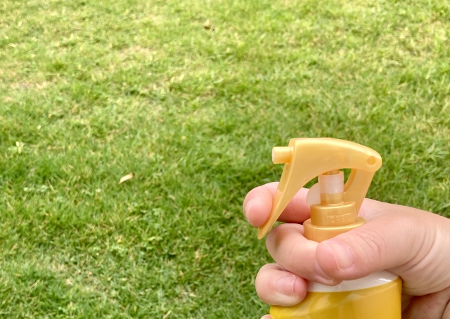 外で虫よけスプレーを噴射する